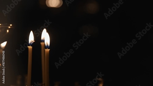 video captures sequence of three candles burning steadily, with flames dancing gently and casting warm light against dark backdrop, creating  tranquil scene