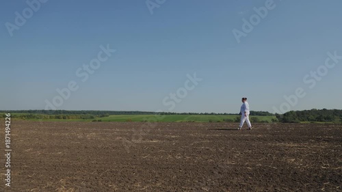 Woman in white clothes walking in a plowed field