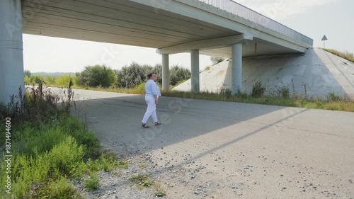 Woman in white clothes walking under a concrete bridge