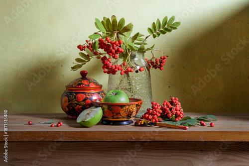 Still life with red rowan berries and wooden utensils painted with Khokhloma style