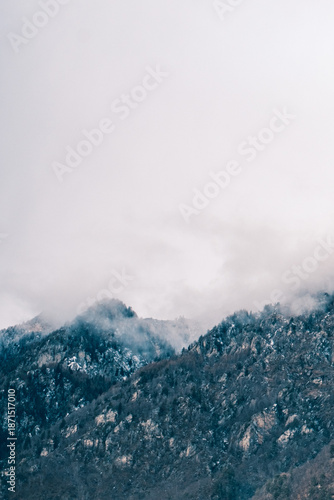 Moody mountain landscape with foggy forested peaks and large copy space, minimal alpine nature background
