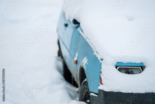 Detail view of front side of car with broken headlight. Old forgotten snow covered car 