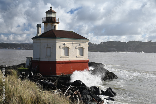 Foto Coquille river lighthouse sitting on the north jetty overlooking the bay under a blue sky with cotton ball clouds