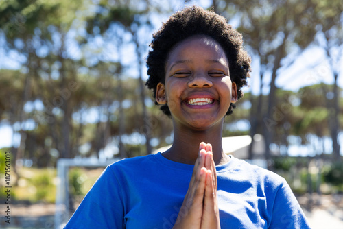 African youth female standing at park wearing blue t-shirt smiling with eyes closed by white frame