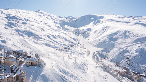 Aerial photo from dronet to Sierra Nevada ski resort on a sunny winter day in the mountains, Spain. Sierra Nevada is the largest mountain range near the city of Granada in Spain with snow. Sierra Neva