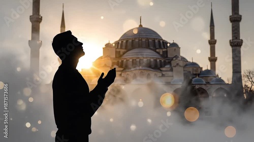 Praying man silhouette with blurred mosque at sunrise