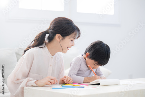 Foto A toddler enjoying learning while opening a notebook under Mom's watchful eye En