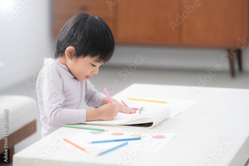 Fotografie 白いリビングで色鉛筆を使い、夢中でお絵かきやぬり絵を楽しむ幼児　想像力や創作力を育む、非認知能力を育てる