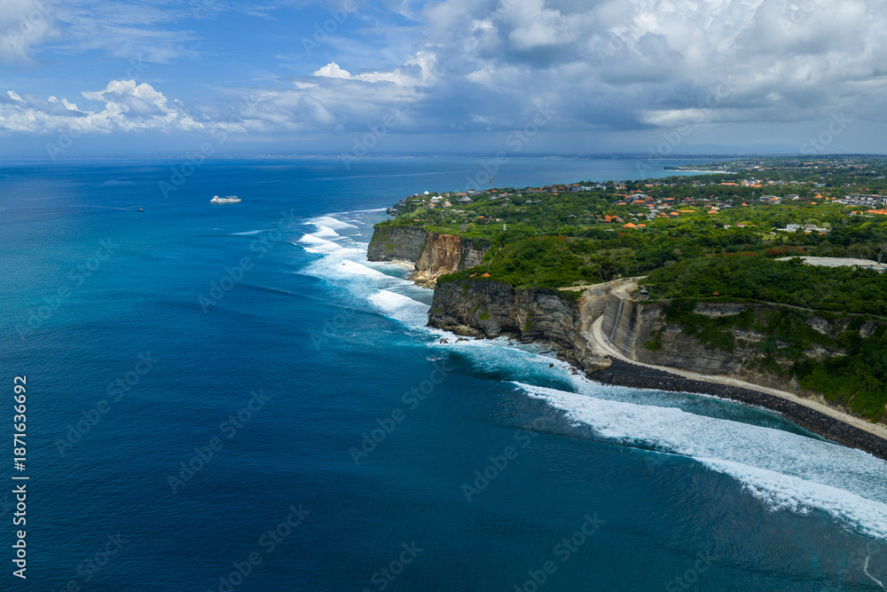 Obraz premium Aerial view of the Uluwatu coastline near Uluwatu Temple showing dramatic cliffs, ocean views, and nearby new construction during warm afternoon light in Bali, Indonesia.