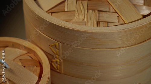 A close-up of a traditional Chinese bamboo steamer with rising steam.