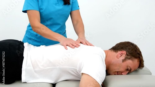 Chiropractor applies gentle downward pressure on patient's upper back for spinal adjustment and relief