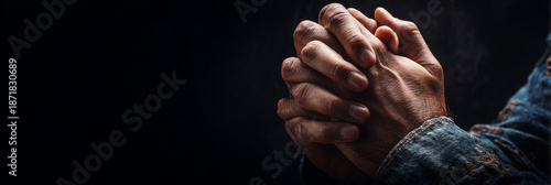 Close up of man hands folded in prayer on dark background