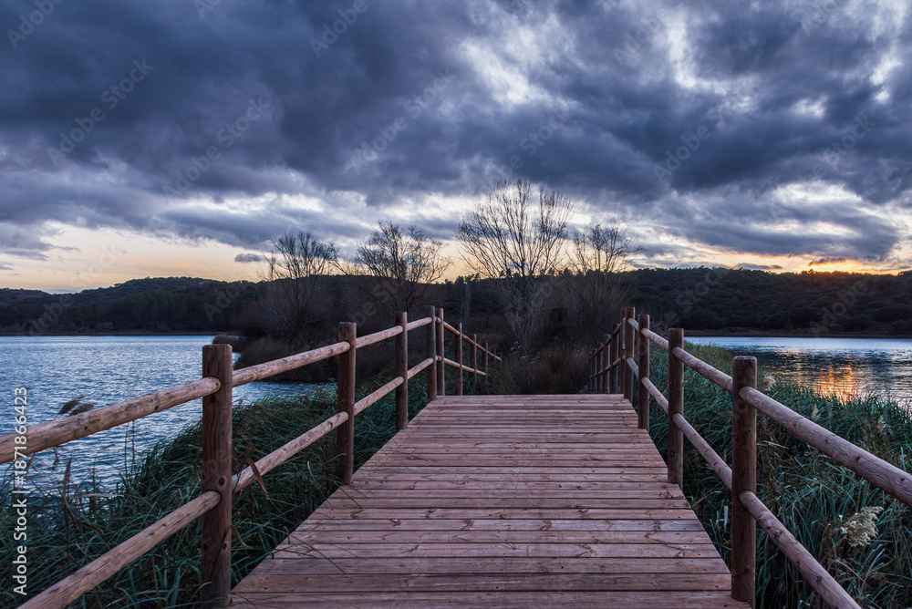 Obraz premium Wooden footbridge leading to a small island in Laguna Colgada, Lagunas de Ruidera, Spain.