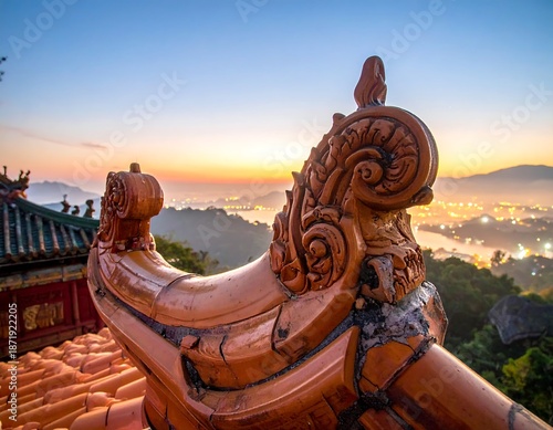 Ornate, orange-tiled roof detail of a historic structure. A soft sunrise illuminates the distant cityscape and mountains