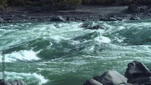 Green River Rapids Crashing Over Rocks With Frothy Foam And Fast Current, Rugged Boulders Lining Shore, Emerald Water Churn, WindWhipped Spray, Dramatic Mountain Setting Ideal For Nature Study