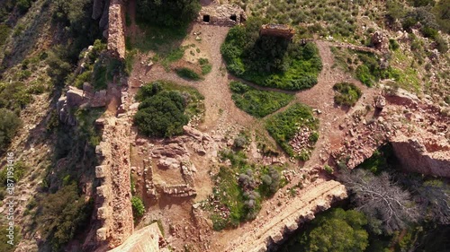 Aerial view of ancient castle ruins near Serra village, gently rising to reveal rocky terrain and pine forests across the Sierra Calderona Natural Park in the Valencia region of Spain