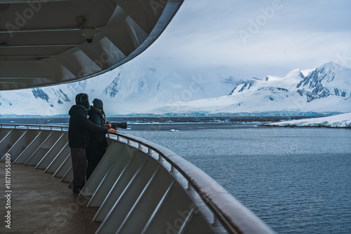 Фотография Antarctica Man Woman in Love Stand Together on Deck Looking at Frozen Landscape Glaciers Snow Covered Mountains
