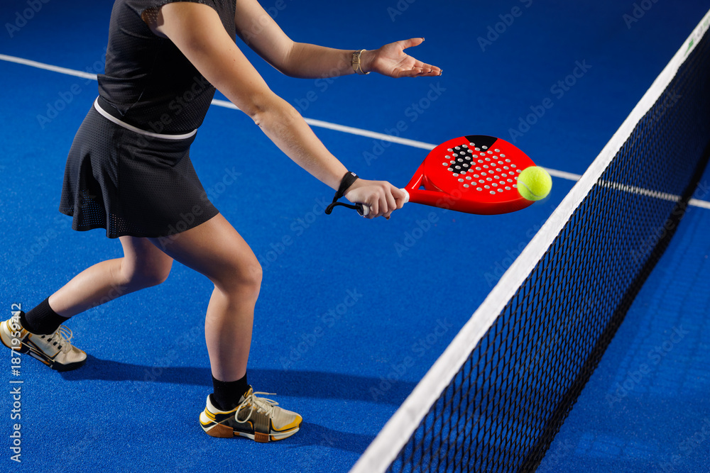 Fototapeta premium Indoor padel net volley by female player on blue court