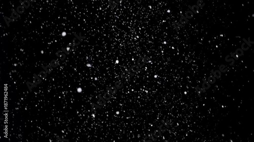 Snow falls gently in a dark night with light reflections and shadows