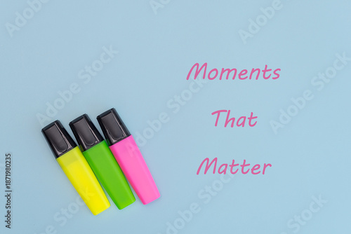 Three highlighters in yellow, green, and pink arranged on a light blue background with the text 'Moments That Matter'.