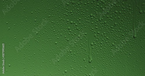 Close up of wet glass with dripping water drops and streaks of rain, on a bright green chroma key background, perfect for visual effects and background replacement. Slow motion.