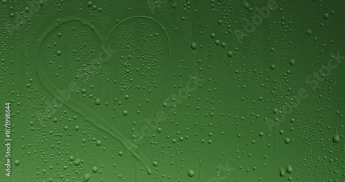 Silhouette of a finger drawing a heart on a foggy green glass surface covered with water drops and condensation, on a bright green chroma key background. Slow motion.