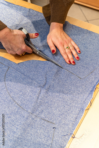 seamstress cuts a piece of fabric with scissors following a line