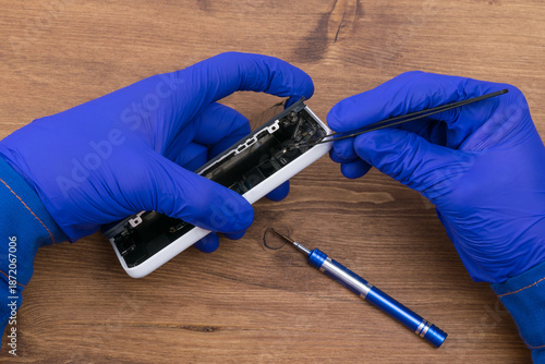 Hands of a craftsman repairing a broken phone display