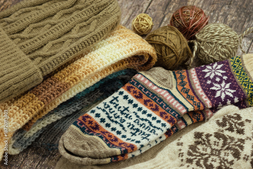 Knitted socks, a hat, mittens, and a scarf for fall and winter. Yarn for knitting socks, hats, mittens, and scarves. Clothing for the cold seasons.