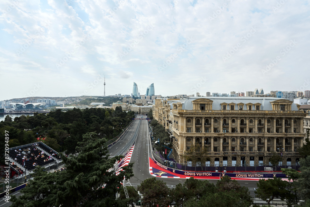 Fototapeta premium BAKU, AZERBAIJAN - SEPTEMBER 19, 2025: A high-angle wide view of the Baku City Circuit featuring trackside Louis Vuitton branding, and the iconic Flame Towers on the skyline during the Formula 1