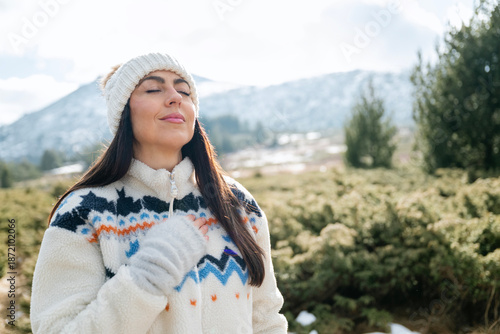 Beautiful woman breathing fresh air in a snowy winter mountain