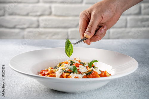Chef Plating Pasta Dish With Fresh Basil