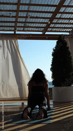 A woman doing an upward-facing dog yoga pose on a beautiful, sunny patio