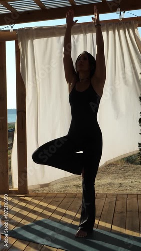 A woman holding a tree pose during an outdoor yoga session