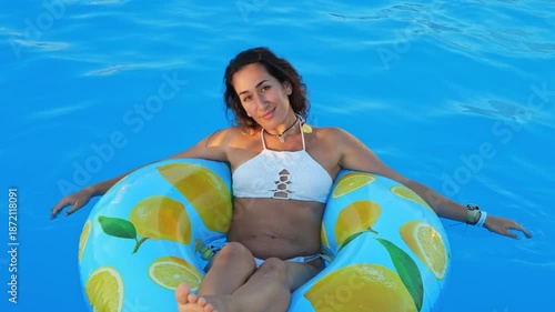 A beautiful woman relaxing in a pool on a lemon-patterned float.