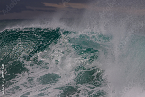 Close-up of a breaking wave in heavy wind with spray from the top