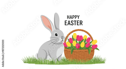 Cute grey easter bunny sitting on green grass next to a traditional wicker basket filled with vibrant pink and yellow tulip flowers.
