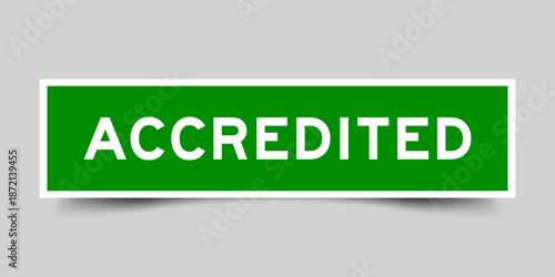 Green color square shape sticker label with word accredited on gray background