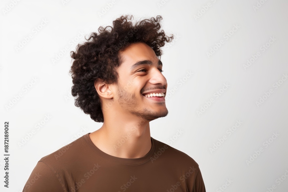 Obraz premium Young handsome man with curly hair smiling and looking away on a white background