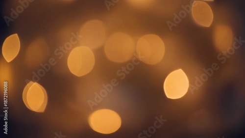 Abstract golden shimmering light bokeh background video loop for celebration and festive holiday events, soft warm blurry out-of-focus particles creating a magical atmosphere.