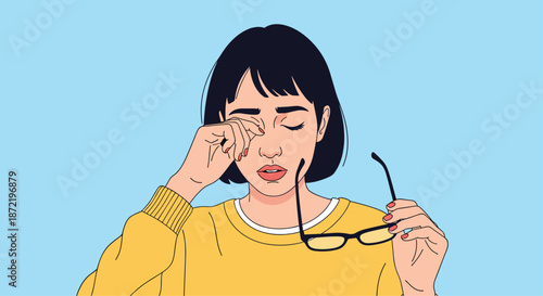 Overworked young woman with short black hair taking off her glasses and rubbing her tired and strained eyes after a long day of work.