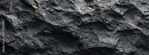 Close-up of rough, dark, textured rock face, showing fissures and variations
