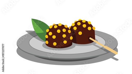 Two round chocolate dango sweets covered with yellow bits are served on a grey plate with a green leaf and a wooden skewer as a tasty snack.
