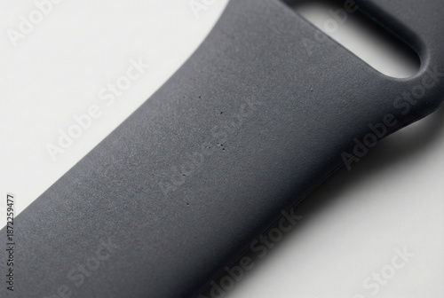 A macro close-up shot of a matte black silicone smartwatch strap, showcasing its fine micro-grain texture and subtle surface imperfections under soft, directional studio lighting.