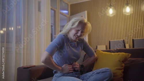 Stomach cramps, hands and woman on sofa in home with menstruation, periods or constipation.