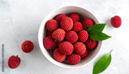 Lychees in a bowl with leaves on a white background.