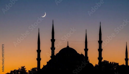 Silhouette of a mosque at dusk with a crescent moon.