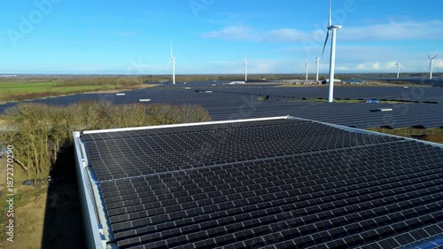 Aerial view of Chelveston Wind Farm displaying a vast array of solar panels, with wind turbines in the background, Wellingborough, United Kingdom.