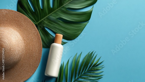 Light tan straw hat, white lotion bottle, and tropical leaves on a pastel blue background