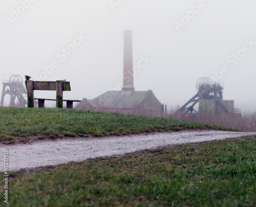 Landscape image with an old coal mine in the misty background.